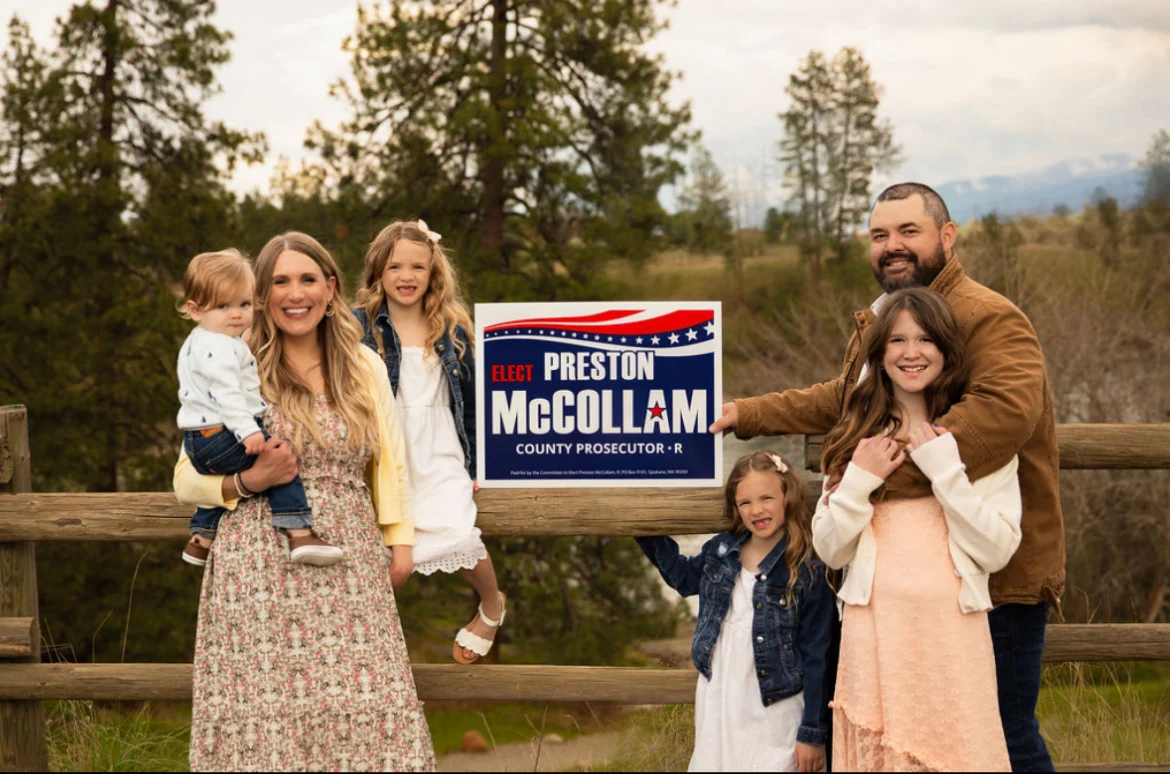 Preston McCollam with his wife and four children beside a campaign sign